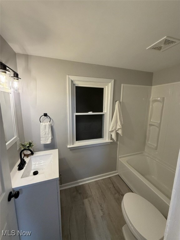 full bathroom with shower / tub combination, vanity, hardwood / wood-style flooring, and toilet