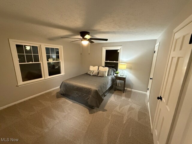 carpeted bedroom featuring ceiling fan and a textured ceiling