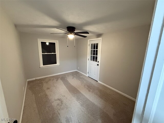 carpeted empty room featuring ceiling fan and a textured ceiling