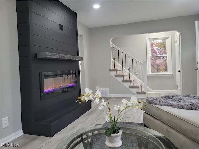 living room with a large fireplace and wood-type flooring