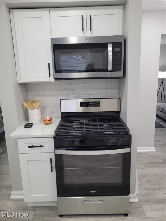 kitchen featuring white cabinets, appliances with stainless steel finishes, and tasteful backsplash