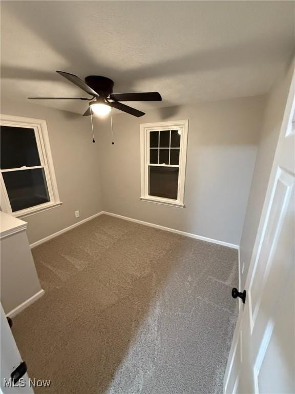 empty room featuring ceiling fan and carpet