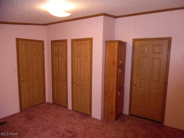 unfurnished bedroom featuring crown molding, a textured ceiling, two closets, and carpet floors