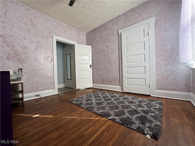 interior space with dark wood-type flooring, a textured ceiling, and ceiling fan