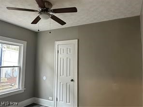 unfurnished room with a textured ceiling and ceiling fan