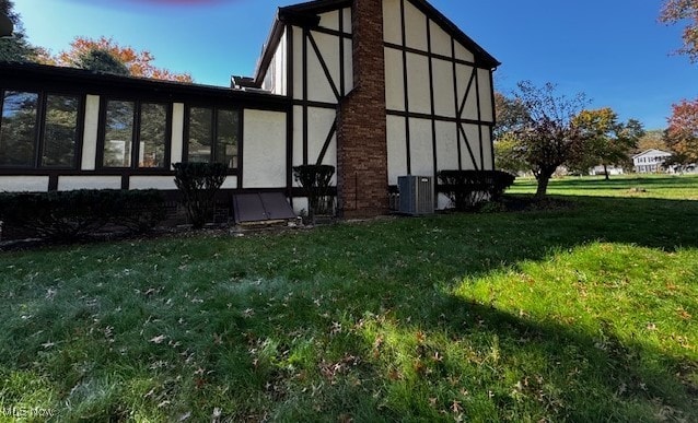 back of property featuring a yard and central AC