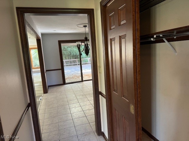 hall with light tile patterned floors and an inviting chandelier