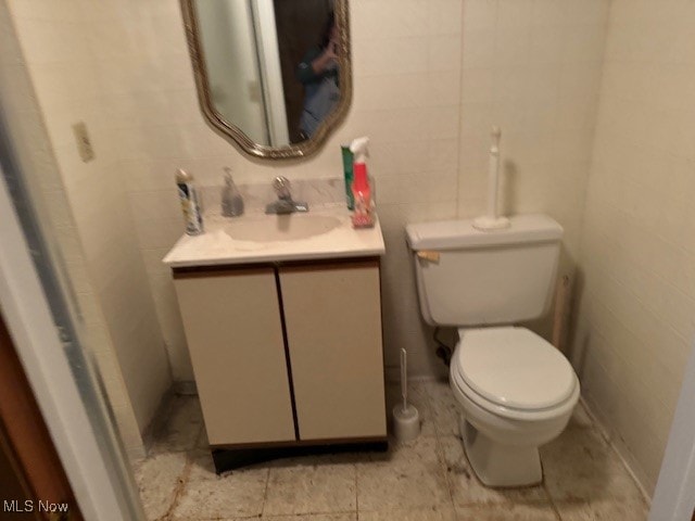 bathroom with vanity, tile walls, and toilet