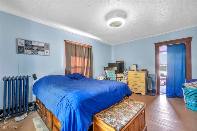 bedroom with a textured ceiling, radiator, and light wood-type flooring