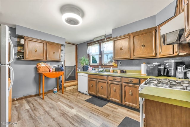 kitchen with backsplash, sink, light hardwood / wood-style flooring, and white appliances