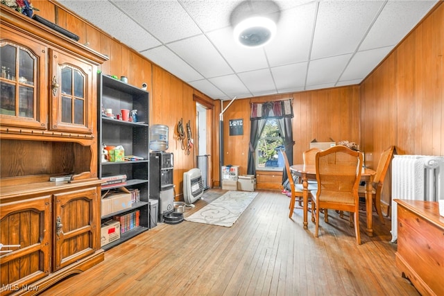 interior space featuring light hardwood / wood-style floors, a drop ceiling, and wood walls