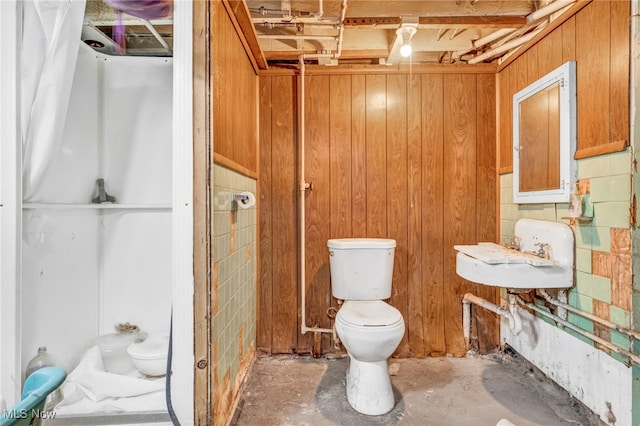 bathroom featuring sink, concrete flooring, toilet, and wood walls