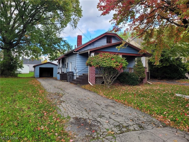 view of front of property featuring a garage, a front lawn, and an outbuilding