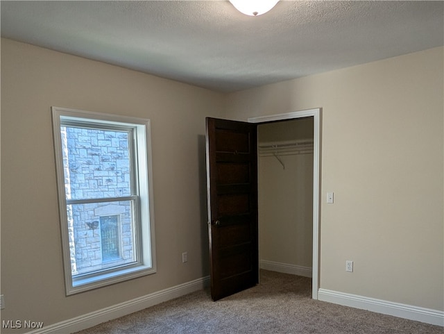 unfurnished bedroom featuring a textured ceiling, carpet floors, and a closet