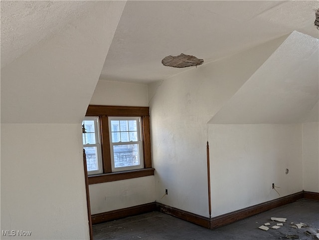 additional living space with vaulted ceiling and a textured ceiling