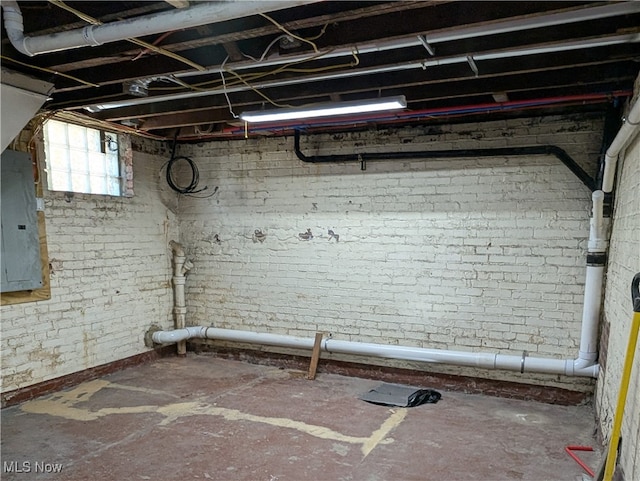 basement featuring brick wall and electric panel