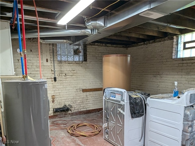 interior space with brick wall, electric water heater, and washer / clothes dryer