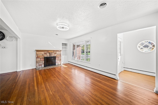 unfurnished living room with hardwood / wood-style flooring, baseboard heating, and a stone fireplace