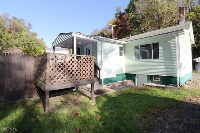 back of property featuring a deck and a lawn