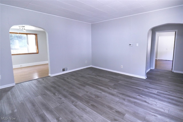 spare room with an inviting chandelier and dark hardwood / wood-style flooring