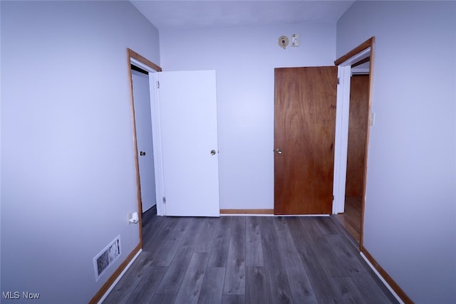 unfurnished bedroom featuring a closet and dark hardwood / wood-style flooring