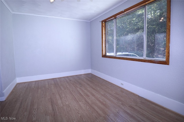 empty room featuring crown molding and wood-type flooring