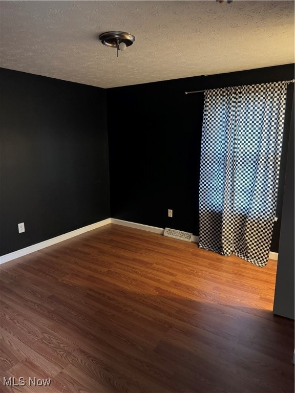 unfurnished room with hardwood / wood-style floors and a textured ceiling