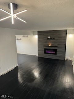 unfurnished living room with dark wood-type flooring and a textured ceiling