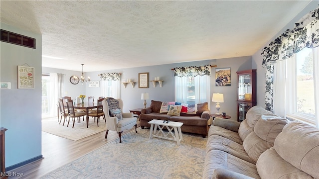 living room with an inviting chandelier, wood-type flooring, and a wealth of natural light