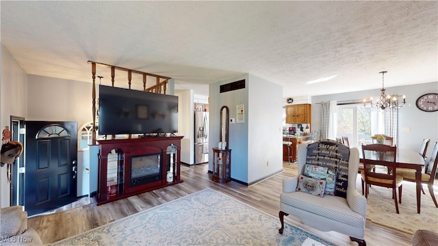 living room featuring light hardwood / wood-style floors, a notable chandelier, and a textured ceiling