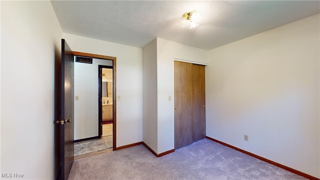 unfurnished bedroom with light carpet, a textured ceiling, and a closet