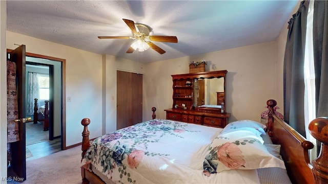 carpeted bedroom with a textured ceiling, a closet, and ceiling fan