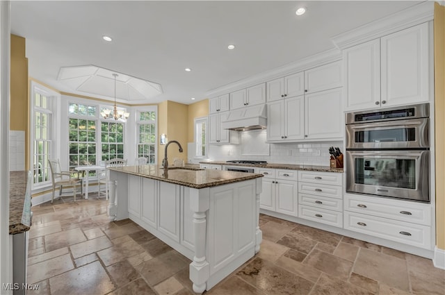 39470 Stillman Ln, Willoughby, OH 44094 - kitchen with dark stone countertops, crown molding, white cabinets, custom exhaust hood, and appliances with stainless steel finishes