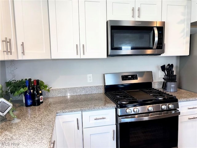 kitchen featuring white cabinets, appliances with stainless steel finishes, and light stone counters