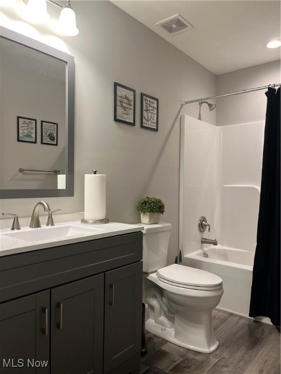 full bathroom featuring shower / bath combo with shower curtain, toilet, wood-type flooring, and vanity