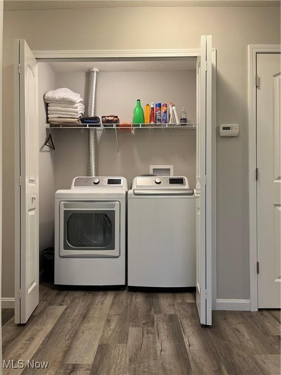 clothes washing area featuring washer and clothes dryer and dark hardwood / wood-style flooring