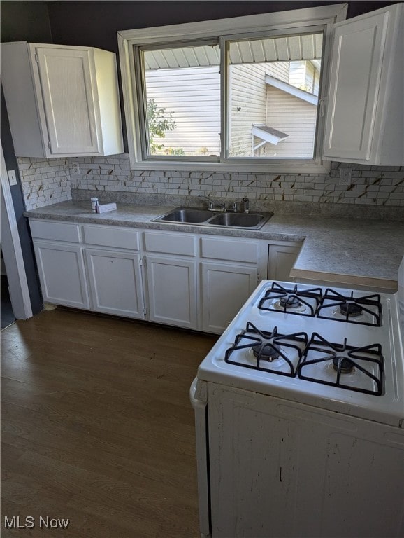 kitchen with tasteful backsplash, dark hardwood / wood-style flooring, white cabinetry, white gas stove, and sink