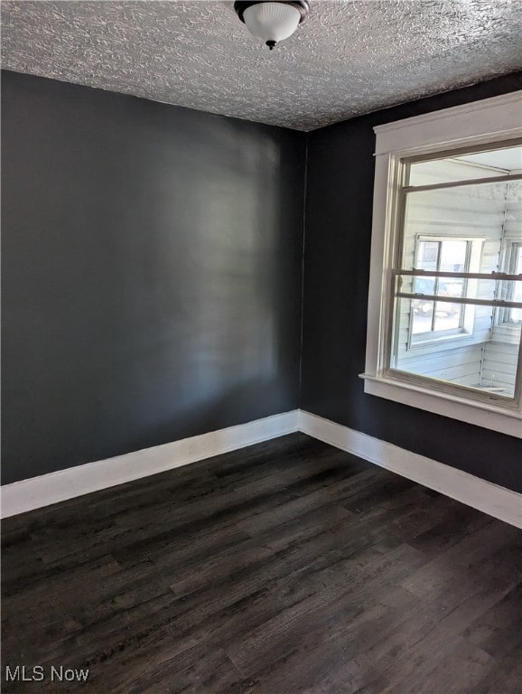 unfurnished room featuring a textured ceiling and dark wood-type flooring