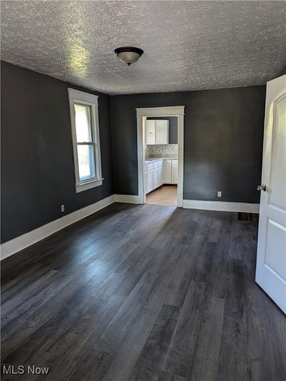 unfurnished living room featuring a textured ceiling and dark hardwood / wood-style flooring