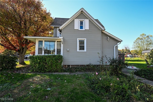 view of side of property featuring a lawn and a sunroom