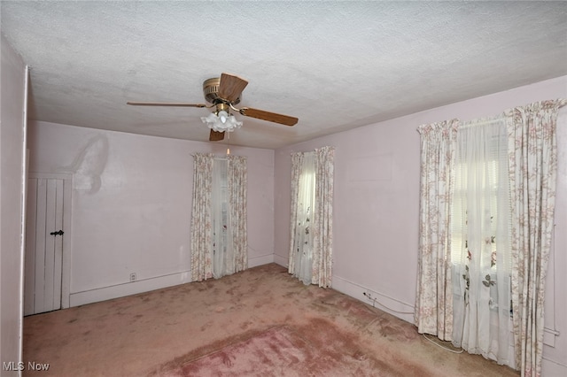 carpeted spare room featuring ceiling fan and a textured ceiling