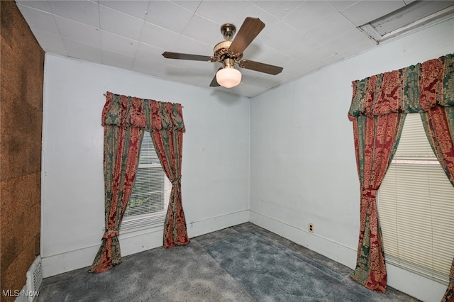 unfurnished room with dark colored carpet and ceiling fan