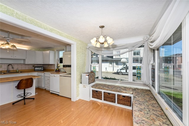 kitchen with white dishwasher, sink, decorative backsplash, and light hardwood / wood-style floors