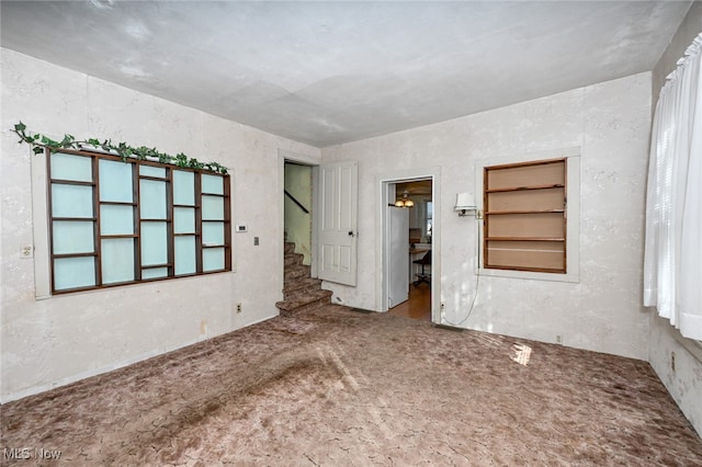 unfurnished room featuring built in shelves and carpet floors