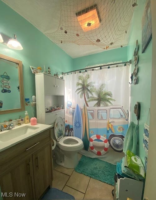 bathroom with toilet, a shower with curtain, vanity, and tile patterned floors