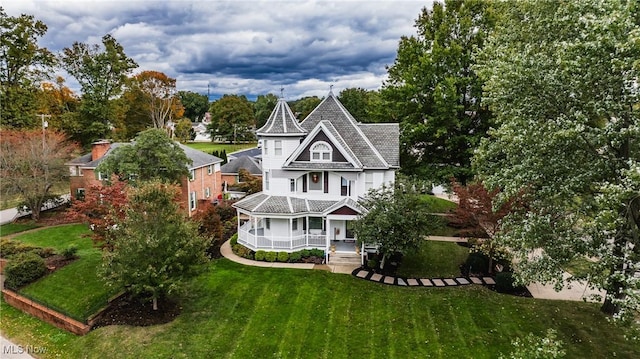 rear view of house featuring covered porch and a yard