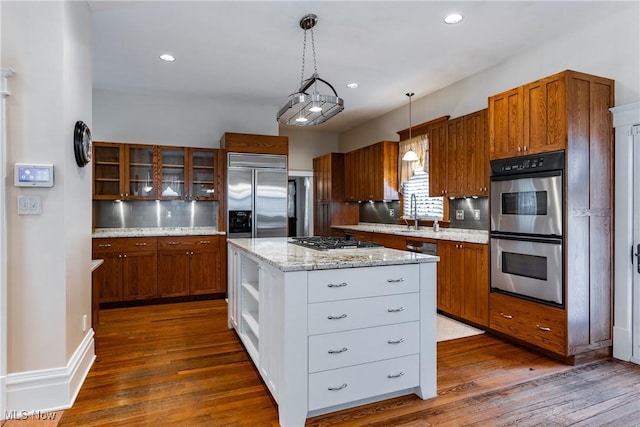 kitchen with a center island, appliances with stainless steel finishes, white cabinets, decorative light fixtures, and backsplash