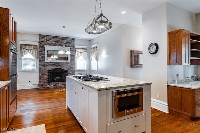 kitchen with hanging light fixtures, dark wood-type flooring, white cabinetry, a fireplace, and stainless steel appliances