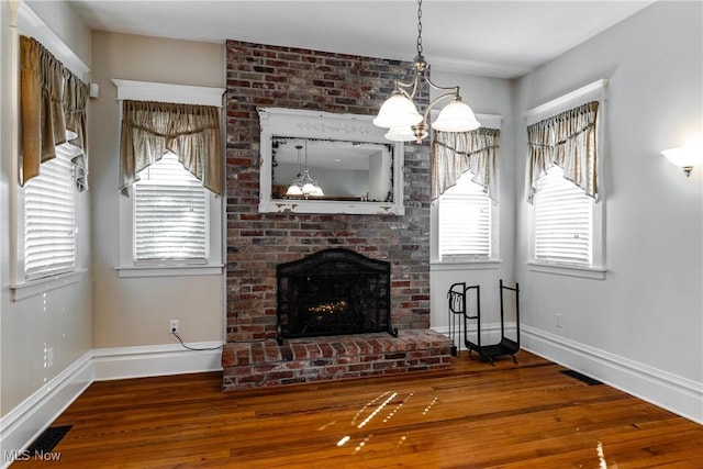 unfurnished living room with a fireplace, hardwood / wood-style flooring, and a chandelier