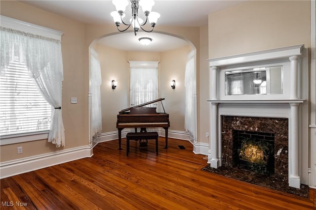 misc room with hardwood / wood-style floors, an inviting chandelier, and a high end fireplace